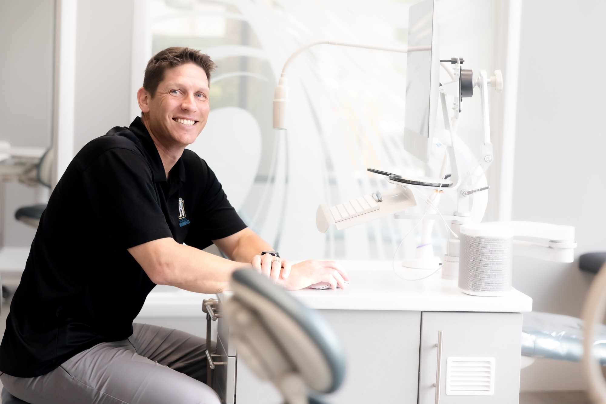 Dr. Jason Rice, orthodontist at Rice Orthodontics, smiling while seated at a treatment station in a modern Jacksonville orthodontic office.